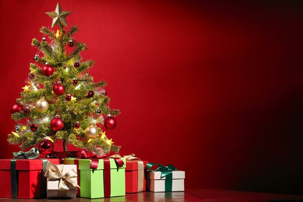 A Christmas tree surrounded by Christmas presents. The background is red.