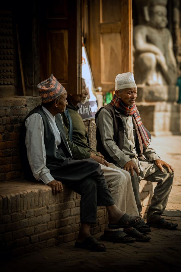 Three men sitting near the street, chewing the fat.