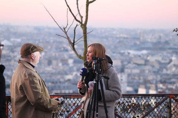 A reporter with a microphone and camera is interviewing a man on the street.