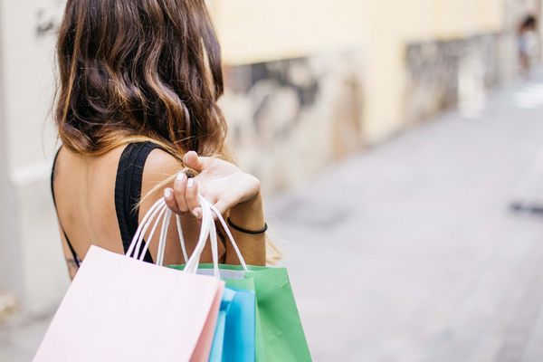 the back of a woman with shopping bags slung over her shoulder